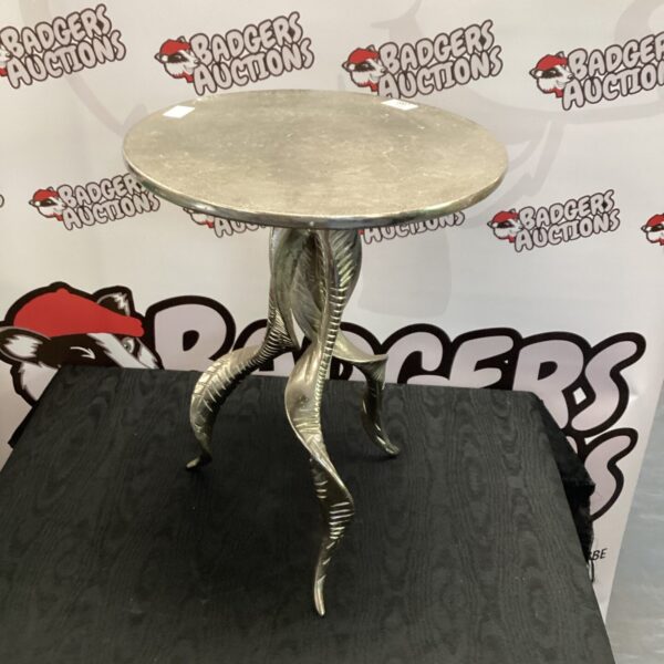 Vintage three-legged metal table with circular top.