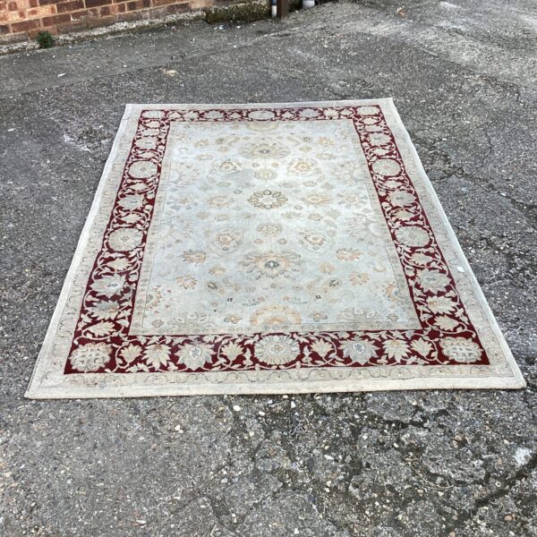 Red floral rug with traditional pattern, approximately 7ft x 5ft.