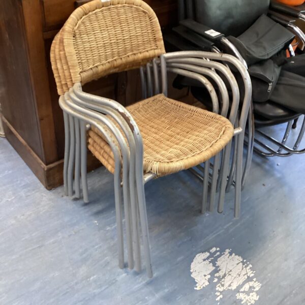 Stack of four vintage raffia chairs with metal frames.