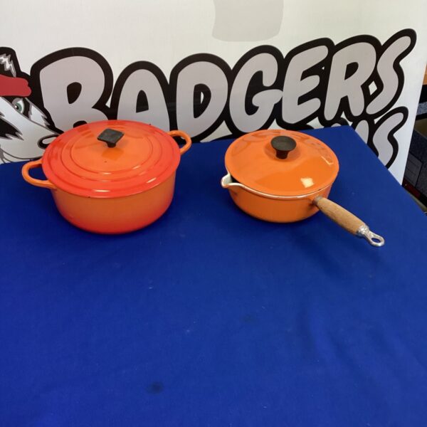 Two vibrant orange Le Creuset pans for cooking and collecting.