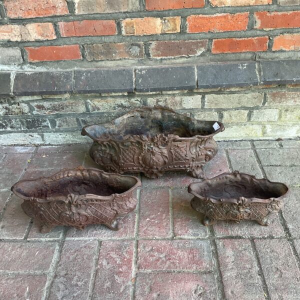 Set of three antique French cast iron planters with floral detailing.