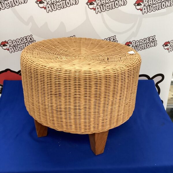 Vintage woven footstool with wooden legs, rustic home decor.