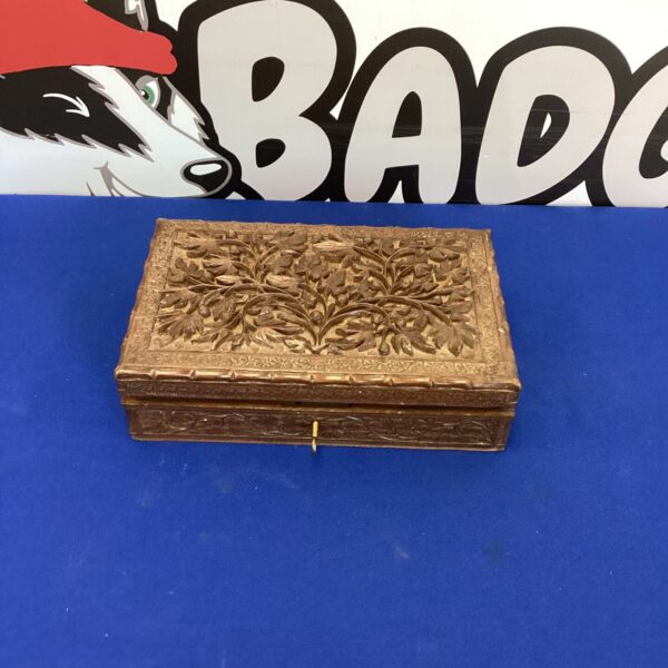 Intricate carved wooden jewellery box on blue background.