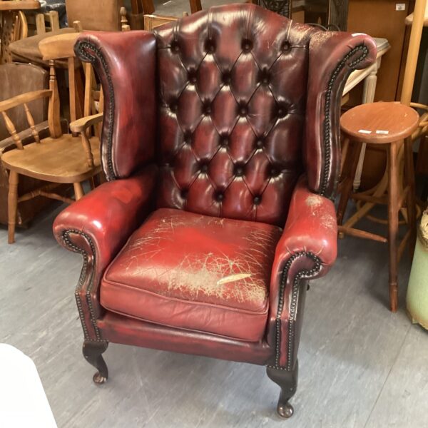 Red leather Chesterfield wingback chair with classic button detailing.