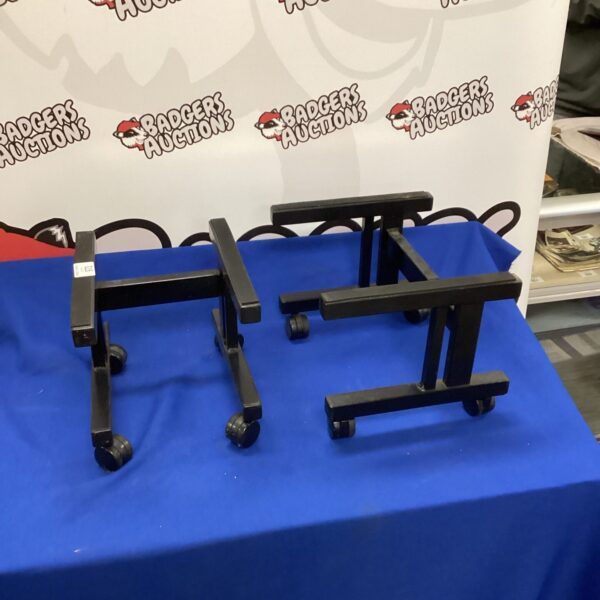 Black two-wheeler speaker stands for home audio setup.