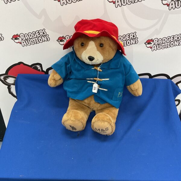 Large M and S Paddington Bear soft toy with blue coat and red hat.