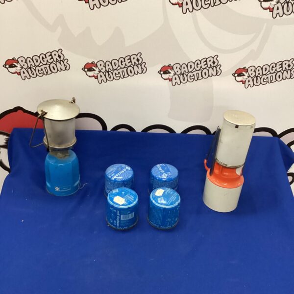 Two vintage enamel camping lamps with gas canisters for outdoor use.