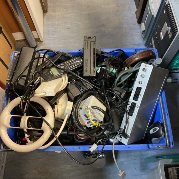 Crate of mixed electrical items including cables and remotes.
