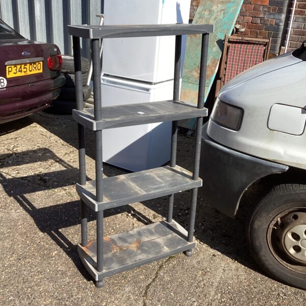 Four-tier plastic shelving unit in a garage setting.