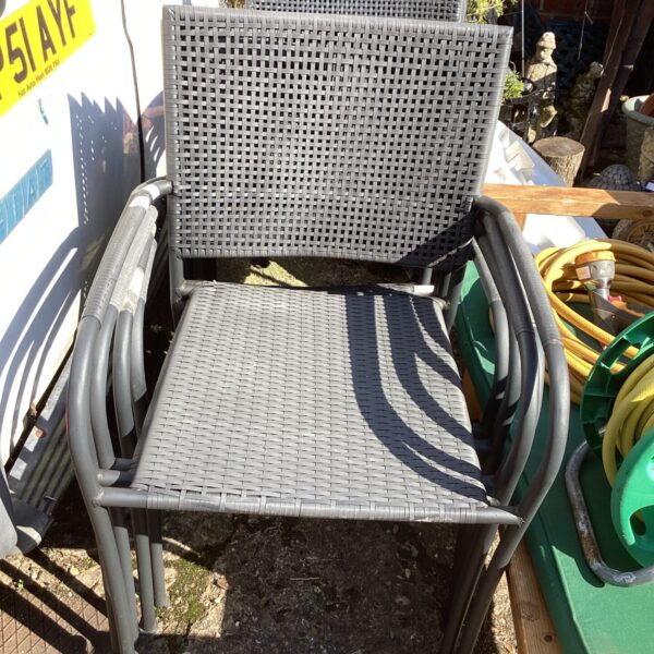 Stack of nine plastic garden chairs for outdoor use.