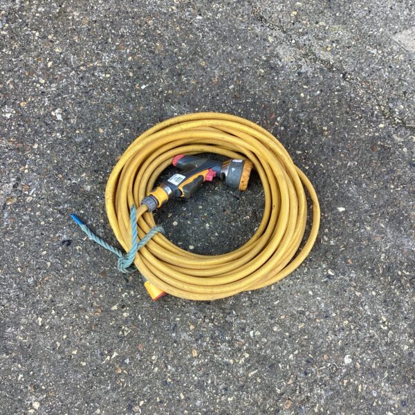 Yellow garden hose with sprinkler head for outdoor watering.