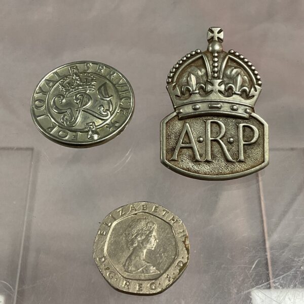Vintage WWII ARP and Loyal Service badges in a display case.