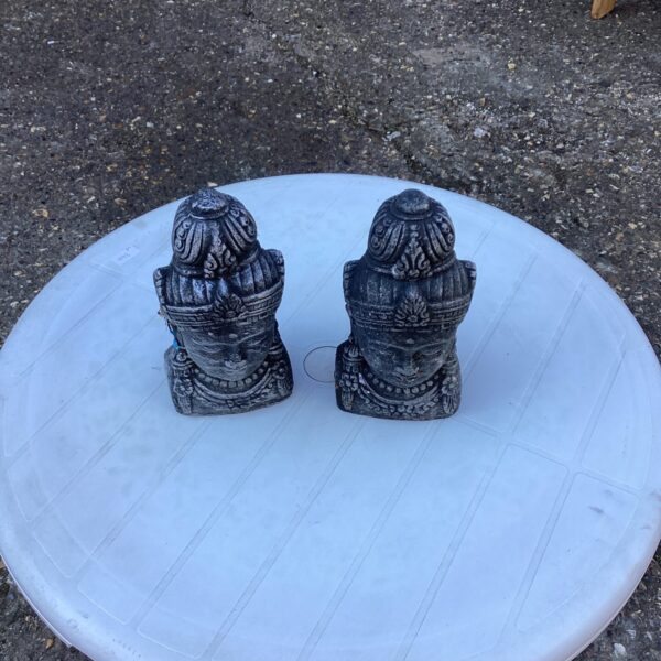 Pair of weathered Buddha garden ornaments in a garden setting.