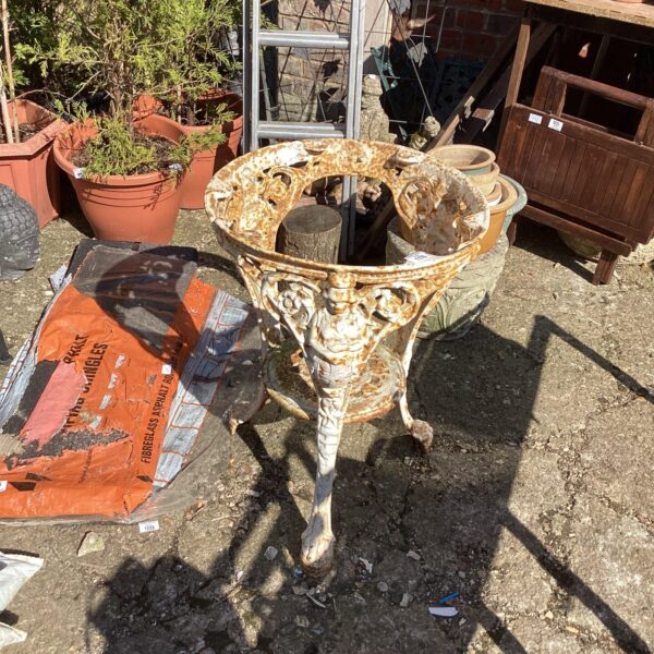 Antique wrought iron garden table base with intricate scrolling details.