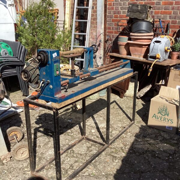 Vintage metal wood turning lathe in a garden setting.
