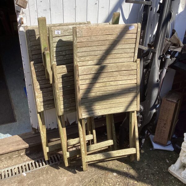 Three vintage teak folding garden chairs in a garden setting.