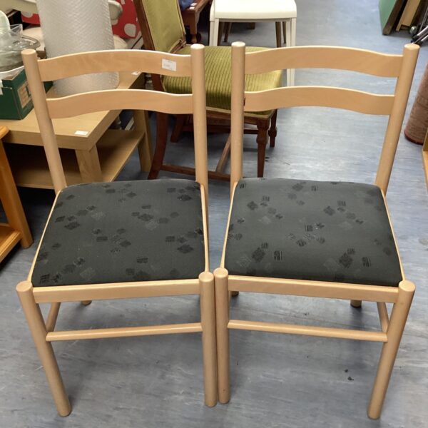 Pair of vintage wooden dining chairs with patterned seats.