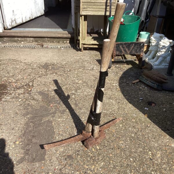 Vintage pickaxe with wooden handle and rusted steel head.