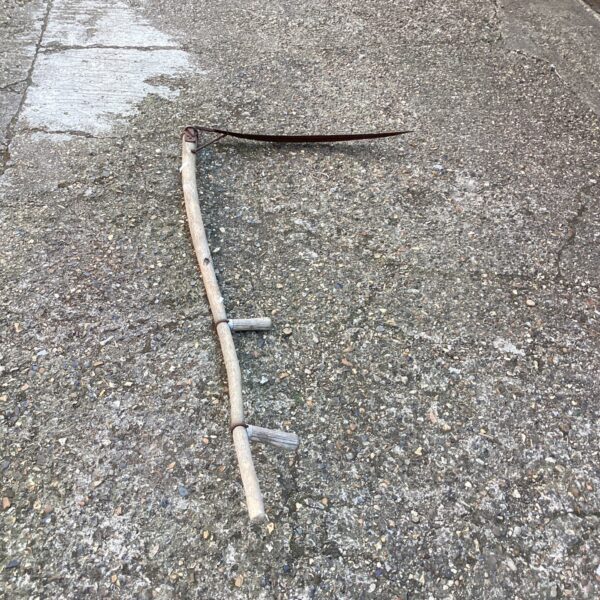 Vintage scythe with curved blade and wooden shaft.