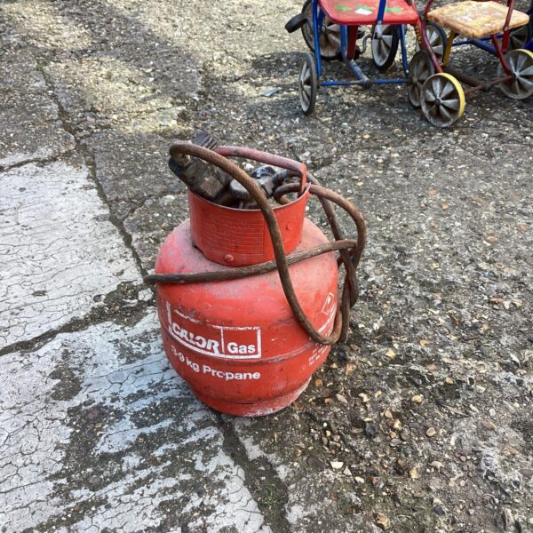 Vintage gas bottle with attached blowtorch for outdoor use.