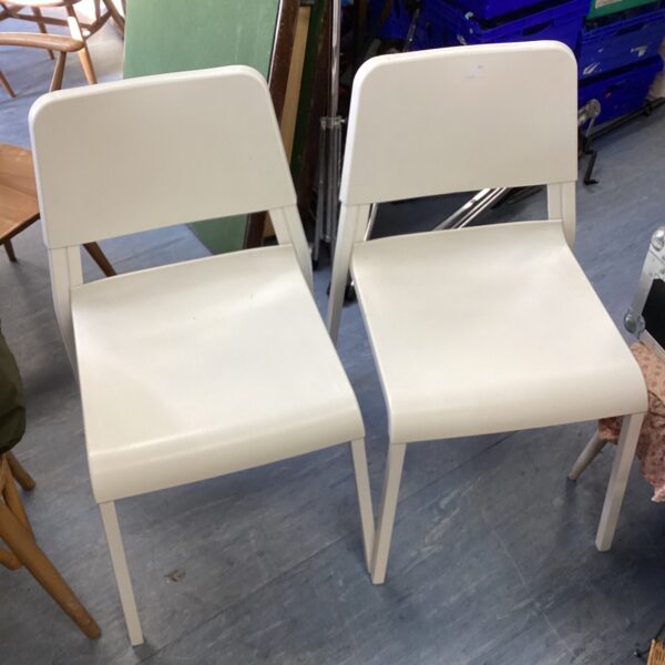 Two white vintage reception chairs with curved backs.
