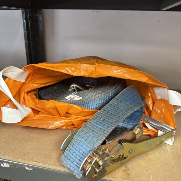 Close-up of a large, used ratchet strap for cargo securing.