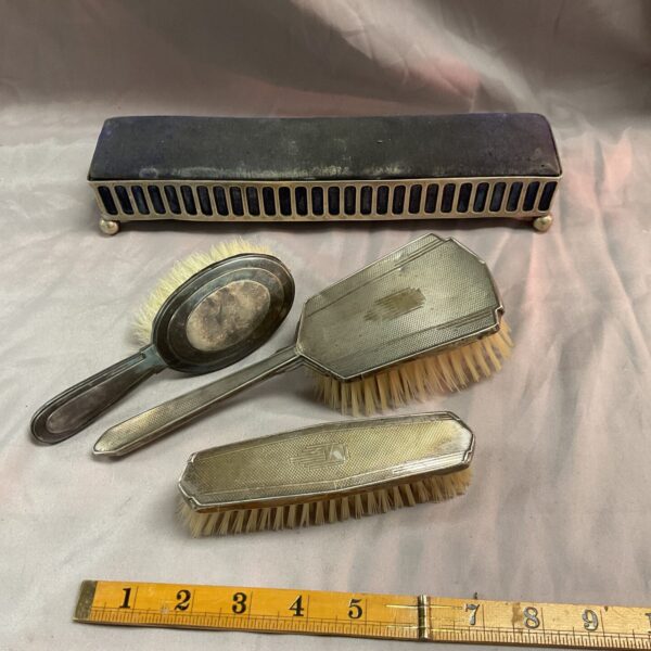 Antique silver backed brush set with ornate detailing.