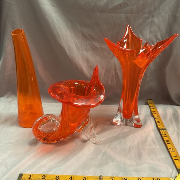 Three vibrant orange art glass vases with sculptural forms.