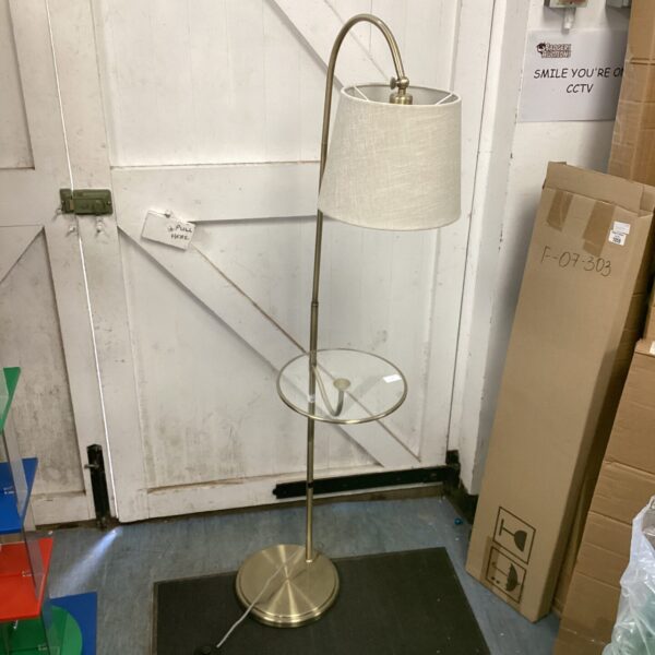 Vintage brass standard lamp with a glass shelf for home lighting.