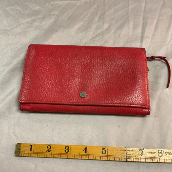 Red vintage Osprey leather purse on ruler.