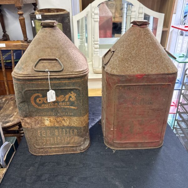 Front view of two vintage Coopers oil cans with rust.