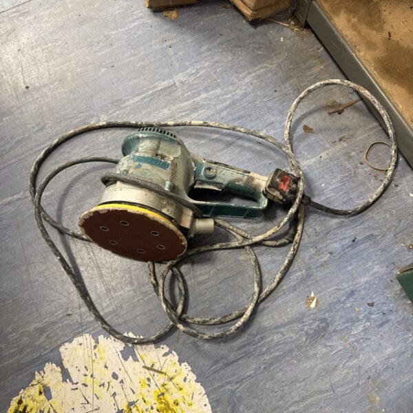 Close-up of a Makita orbital sander, showing wear and tear.