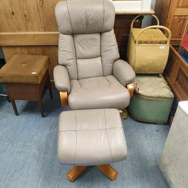 Grey leather recliner chair with footrest in a home setting.