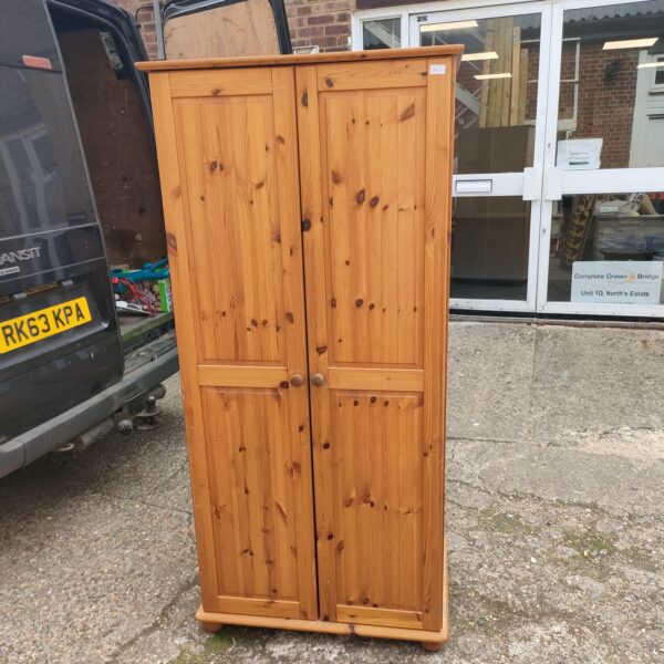 Vintage pine wardrobe with two doors, ideal for bedroom storage.