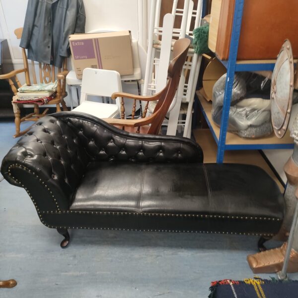 Black leatherette chaise lounge sofa in Victorian style.