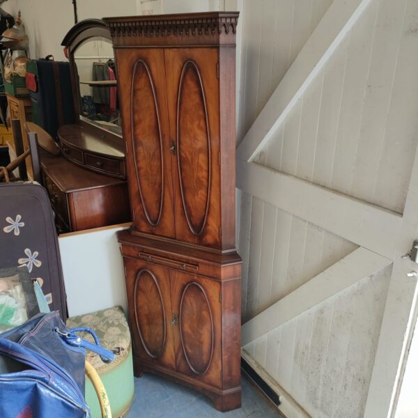 Antique light mahogany corner cabinet for display and storage.