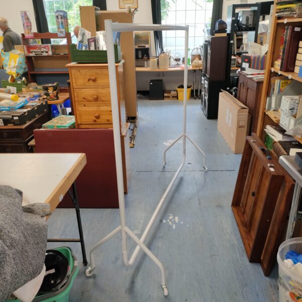 White metal clothing rack in a cluttered room.