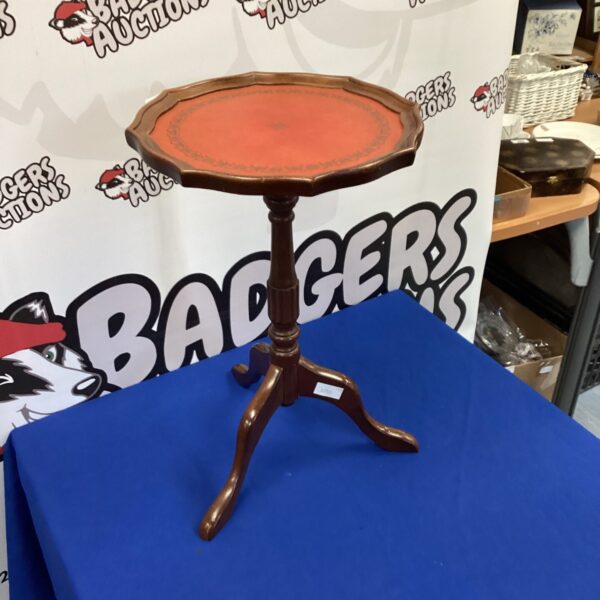 Antique wine table with a circular leather top and mahogany legs.