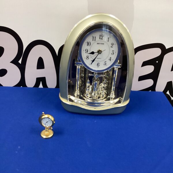Front view of a vintage Rhythm mantel clock with wooden casing.