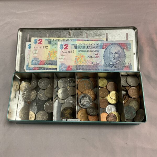 Vintage tin money box filled with Barbadian coins and notes.