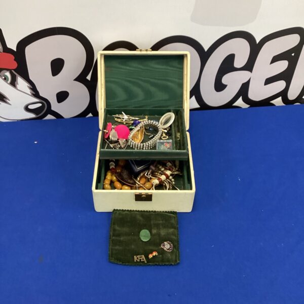 Cream vintage jewellery box filled with assorted jewellery pieces.