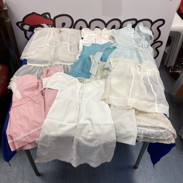 Lot of vintage baby dresses in various styles and colours.