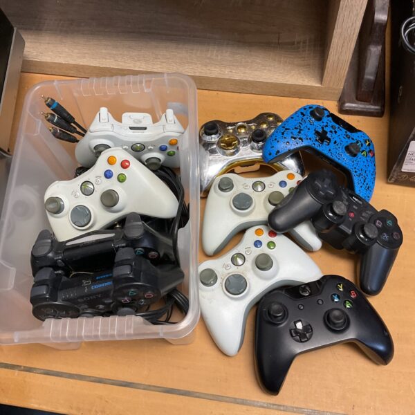 Mixed lot of Xbox 360 and PS3 gaming controllers for sale.