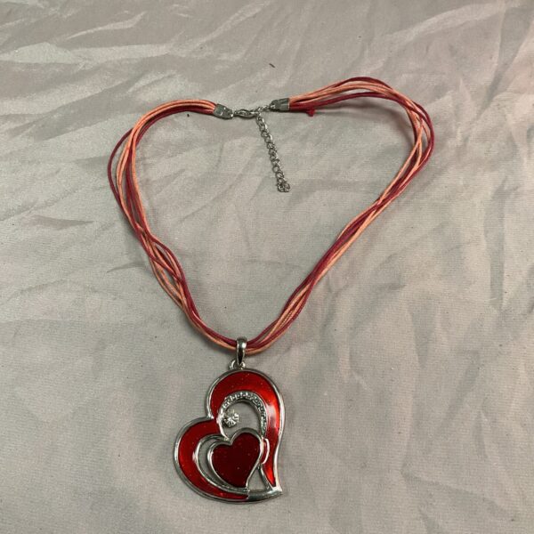 Close-up of a red enamel heart pendant necklace on a cord.