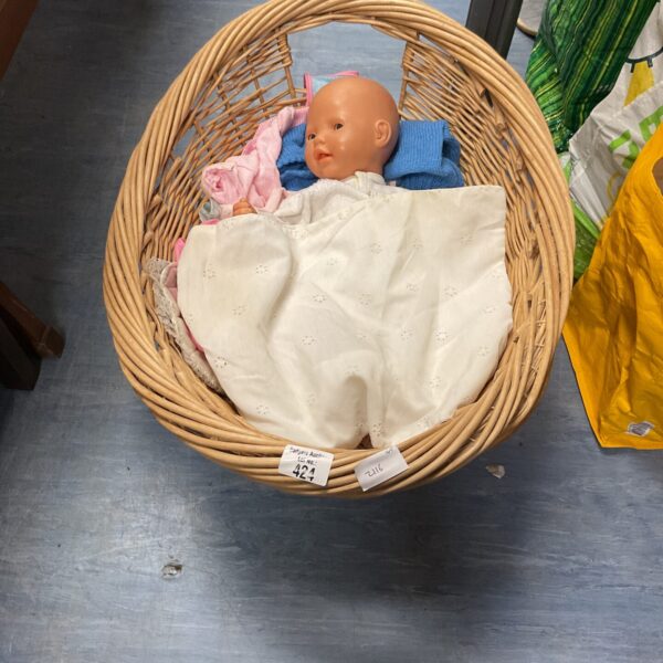 Vintage wicker basket containing a small baby doll for collectors.