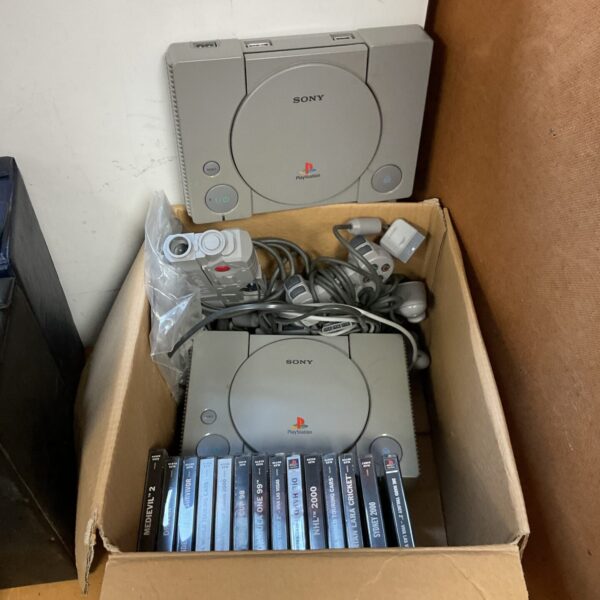 Two Sony PlayStation consoles with controllers and games for retro gaming.