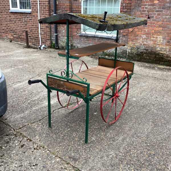 Vintage garden display cart with spoked wheels and canopy.
