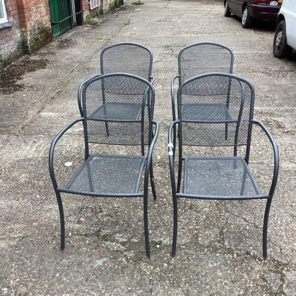 Set of four vintage metal garden chairs in a garden setting.