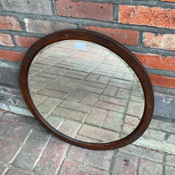 Antique oak framed bevelled circular wall mirror for home decor.