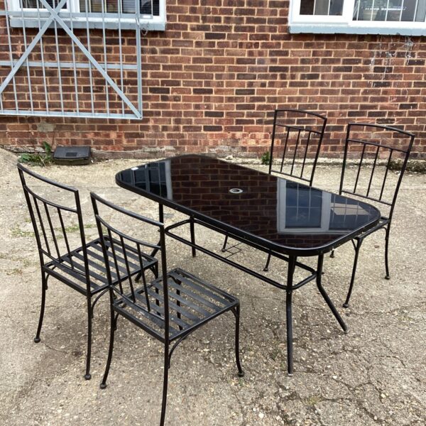 Vintage glass topped dining set with four metal chairs.